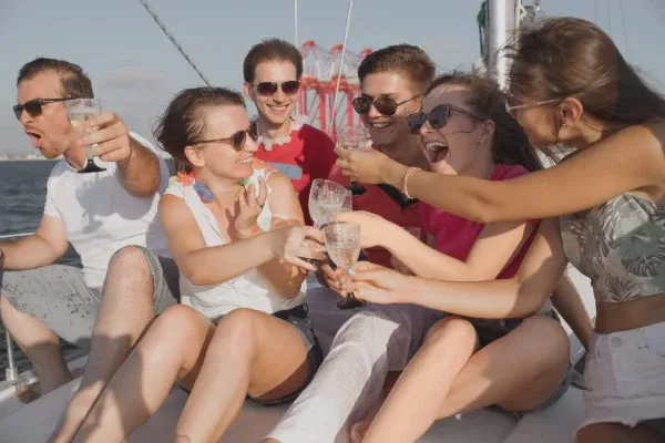 קבוצת חברים צוחקים ומרימים כוסית על סיפון יאכטה בחיפה